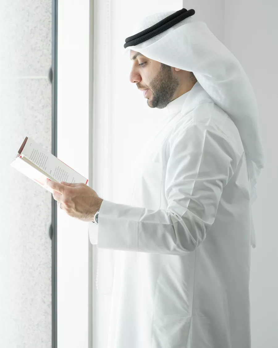 Abdullah Benayan reading beside a window